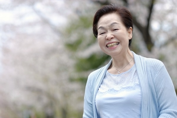 桜を背景に笑顔のお婆さんの写真